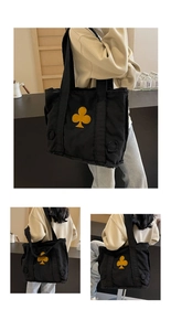 Detail view of black canvas tote bag featuring a yellow club floral pattern and frayed edges