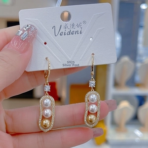 Macro detail of pod-shaped gold drop earrings with triple pearls and S925 silver needles