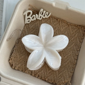 Detailed close-up of a white marble-patterned plumeria hair claw clip on burlap