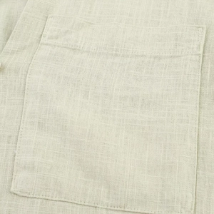 Detailed macro view of beige linen dress fabric with visible pocket and woven texture