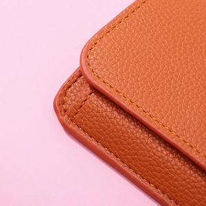 Close-up of orange lychee grain leather wallet with neat yellow stitching details