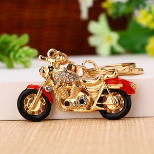 Close-up of gold metal motorcycle keychain with red seat and sparkling rhinestones