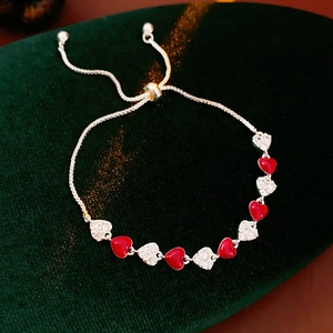 Detailed macro view of silver heart bracelet with red enamel and pavé stones on velvet
