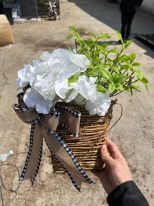 Detail of a rustic woven basket with white hydrangeas and a burlap bow for door decor