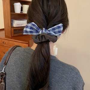 Detail of blue plaid bow scrunchie on brown fabric for elegant ponytail hair styling