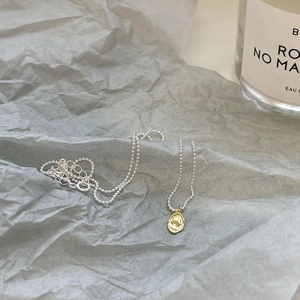 Detail of vintage silver bead chain with gold oval portrait relief coin pendant