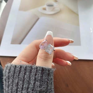 Detailed close-up of a pear-shaped pink and rectangular white zircon ring on a model hand