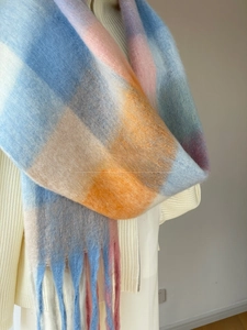 Close-up of a soft gradient checkered scarf with thick fringe detail and cozy mohair texture