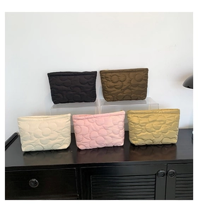Quilted floral cosmetic bags in five colors displayed on a modern storage shelf