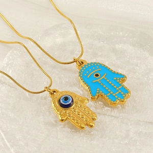 Vintage Hamsa Hand and Evil Eye gold necklace with blue enamel on a glass tray
