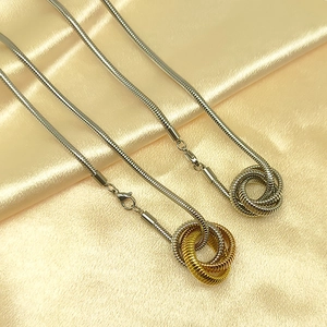 Detail of snake chain necklaces with interlocking triple-ring pendants on satin fabric