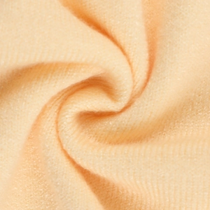 Detalle macro de la suave tela de punto color albaricoque con textura afelpada y acabado ondulado