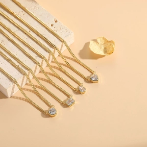 Detailed macro shot of gold necklaces with diverse zircon charms on textured stone