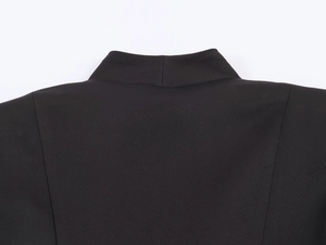 Detail shot of the stand collar and structured shoulder of a black pleated hem blazer
