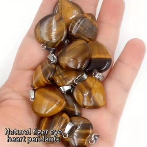 Natural tiger eye heart pendants with silver metal clasps held in palm view