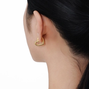 Macro shot of minimalist 18k gold heart-shaped earrings on model for size and style