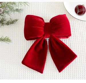 Detailed view of a large dark red velvet bow ornament on a festive holiday background
