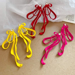 Detailed view of matte bow ribbon stud earrings in red yellow and magenta with rhinestones