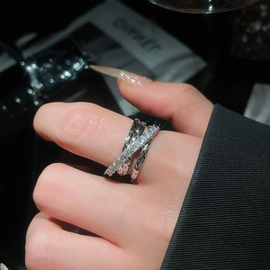 Close-up of three-layer crisscross ring with zircons on model hand in dramatic lighting