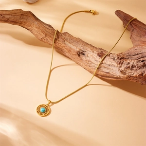 Bohemian gold plated stainless steel necklace with sunburst turquoise pendant on wood