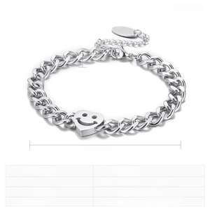 Détail macro du bracelet à chaîne cubaine en acier avec charms cœur gravé et visage souriant