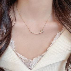 Detail of 18k gold plated necklace featuring butterfly zircon and delicate pearls on model