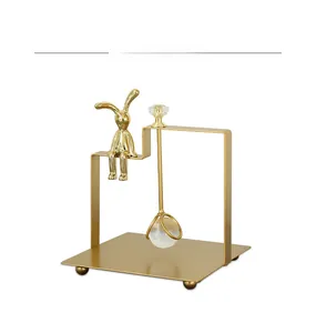 Detail of golden iron rabbit napkin holder with a glass ball on a white background