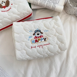 Detail of white heart-quilted pouch with colorful puppy embroidery and zipper closure
