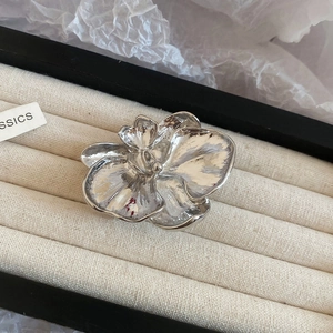 Close-up of silver flower brooch with metallic texture in a premium jewelry display box