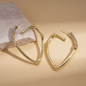 Golden bamboo style hoop earrings with rhinestones on a natural stone background