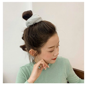 Detail of soft faux rabbit fur hair scrunchie in light grey worn on a ponytail