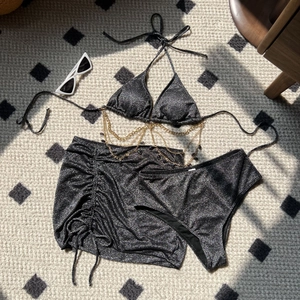 Detailed flat lay of a silver glitter bikini set including skirt and gold waist chain