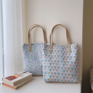 Detail of floral canvas tote bags with reinforced leather straps in a bright setting