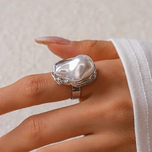 Detailed view of silver adjustable ring featuring a large white baroque pearl on model hand