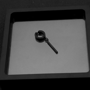 Macro shot of matte black stainless steel clip-on earring with long bar pendant detail
