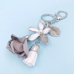 Detail of grey fabric rose keychain with pearl enamel flower and rhinestone fringe