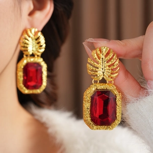 Détail de boucles d'oreilles dorées vintage avec grands cristaux rouges rectangulaires