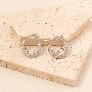 Detailed view of silver horseshoe earrings with intricate vintage floral engravings