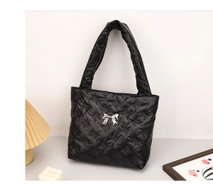 Detail of black quilted tote bag with silver bow buckle and elegant butterfly stitching