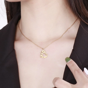 Close-up of golden hollow heart necklace on model with polished stainless steel finish