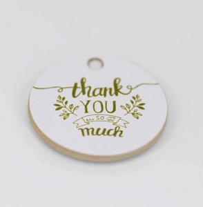 Detailopname van een wit rond cadeaulabel met groene bedanktekst en bladdecoratie
