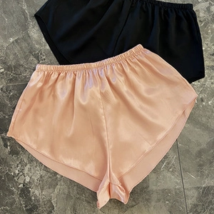 Detailed flat lay of silk satin pajamas pants in peach and black with elastic waist
