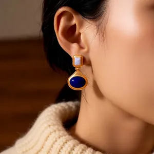 Vintage gold oval earrings with blue gemstone accents shown on model in close-up