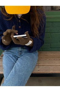 Close-up of women's long brown wool knit gloves with white label on a green background
