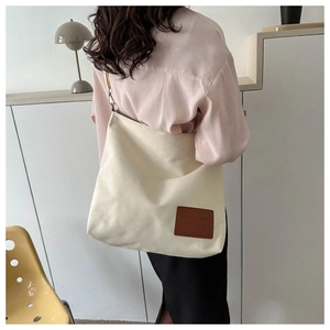 Detail of minimalist canvas tote bag with brown leather patch and large capacity design