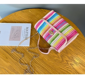 Close-up of rainbow stripe texture bag with pink trim and gold clasp on wooden table
