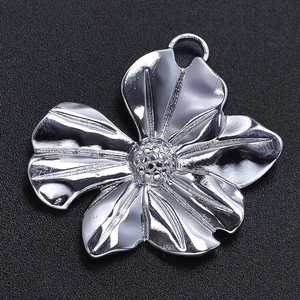 Macro detail of silver stainless steel flower pendant with polished texture and top ring