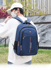 Detail view of water-resistant navy blue backpack with orange zippers and sport text