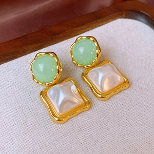 Close-up of vintage resin earrings with green cabochon and faux pearl in gold frames