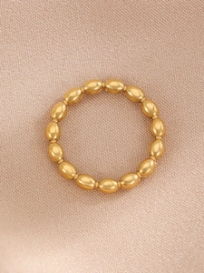 Close-up of golden geometric bamboo bead ring with polished metallic finish on fabric
